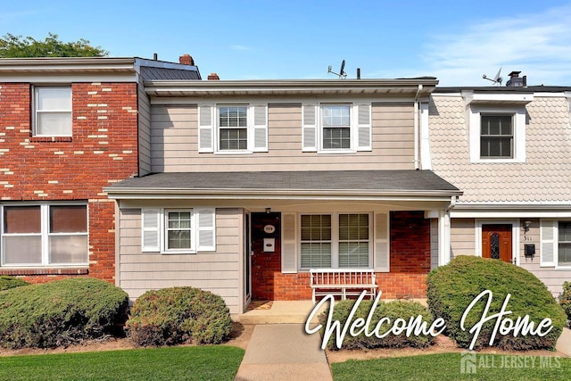 townhome / multi-family property with brick siding, covered porch, and a chimney