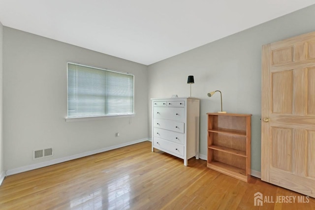 bedroom featuring baseboards, visible vents, and light wood finished floors