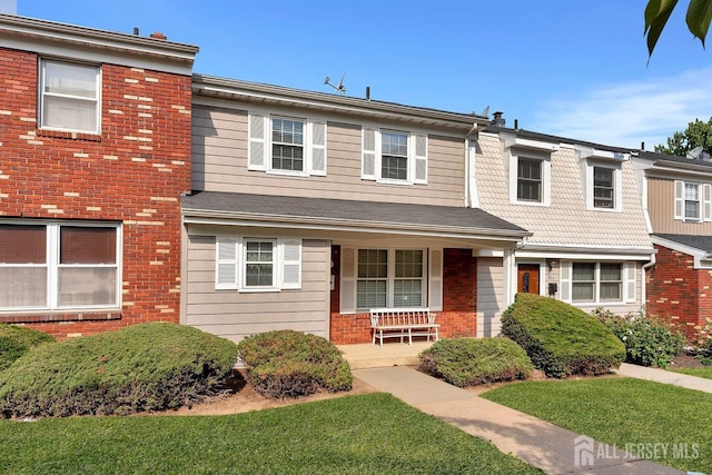 view of property featuring covered porch and brick siding