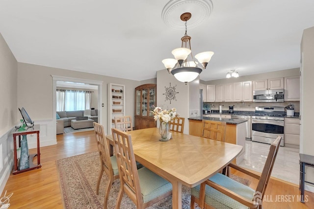 dining room with a wainscoted wall and light wood-type flooring