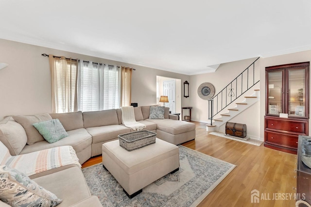 living room featuring light wood-style flooring, stairs, and ornamental molding