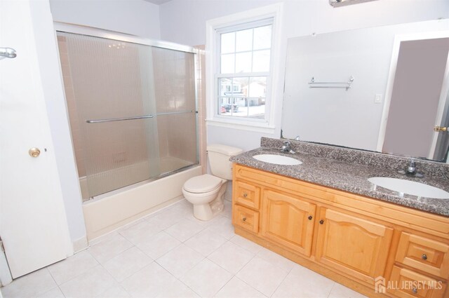 full bathroom featuring toilet, bath / shower combo with glass door, tile patterned floors, and vanity