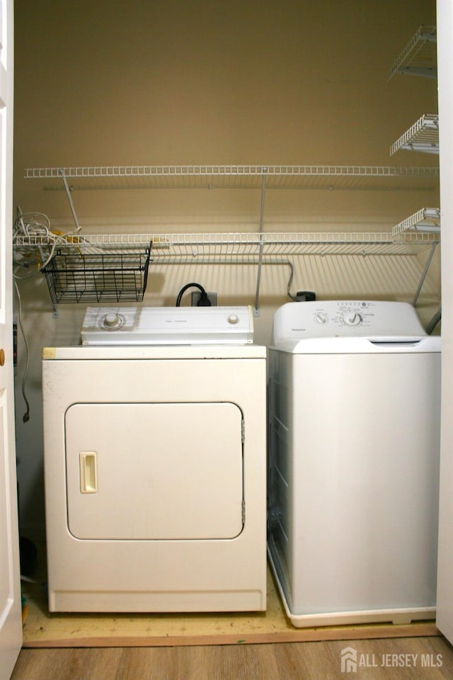 laundry area with washing machine and clothes dryer and wood finished floors