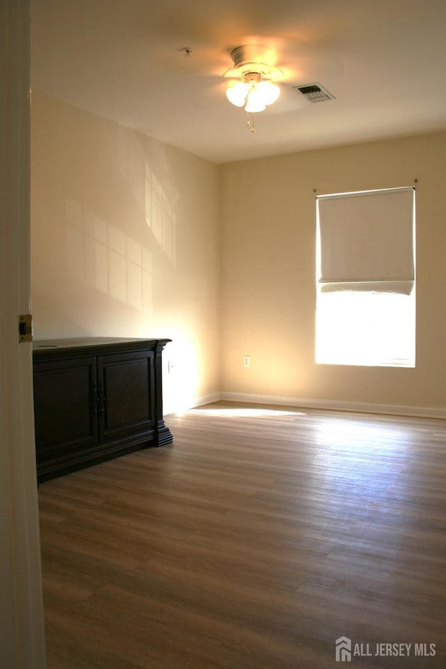 empty room featuring wood finished floors, baseboards, and ceiling fan