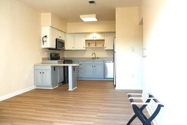 kitchen with stainless steel appliances, white cabinetry, a kitchen breakfast bar, and light hardwood / wood-style flooring