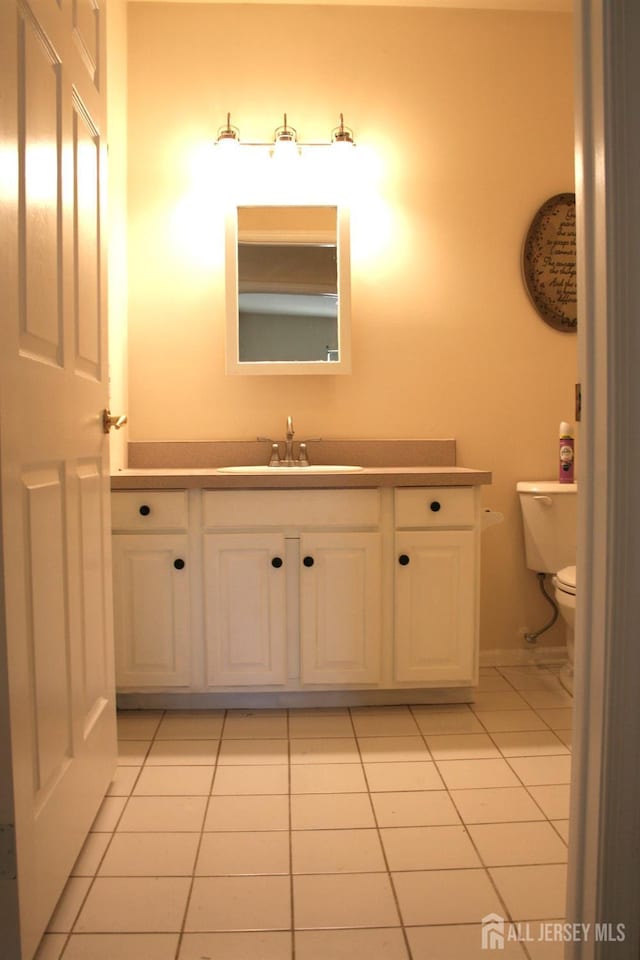 half bath featuring tile patterned flooring, toilet, and vanity