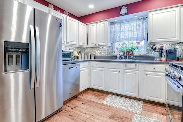 312 Bunnell Pl, Lacey, NJ 08731 - kitchen featuring appliances with stainless steel finishes, light wood-type flooring, white cabinets, decorative backsplash, and dark countertops