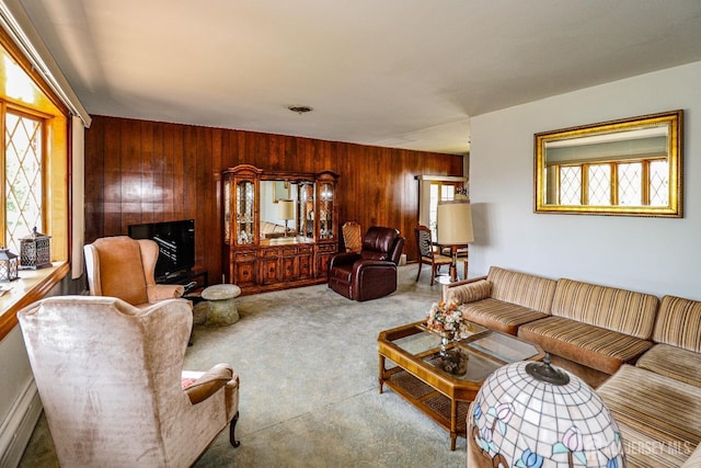 carpeted living area featuring wood walls