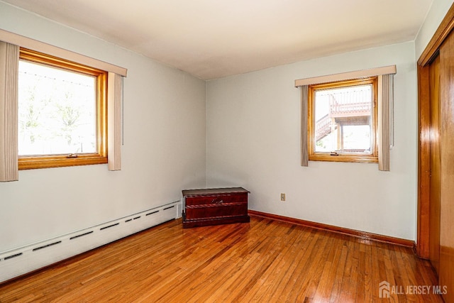 spare room featuring plenty of natural light, light wood-style flooring, baseboards, and baseboard heating