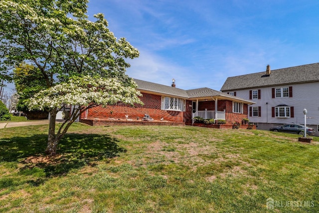 view of front of home with brick siding, a chimney, and a front lawn