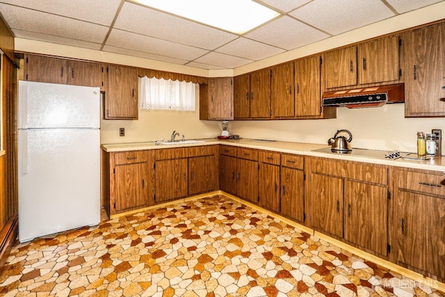 kitchen featuring freestanding refrigerator, black electric stovetop, light countertops, under cabinet range hood, and a sink