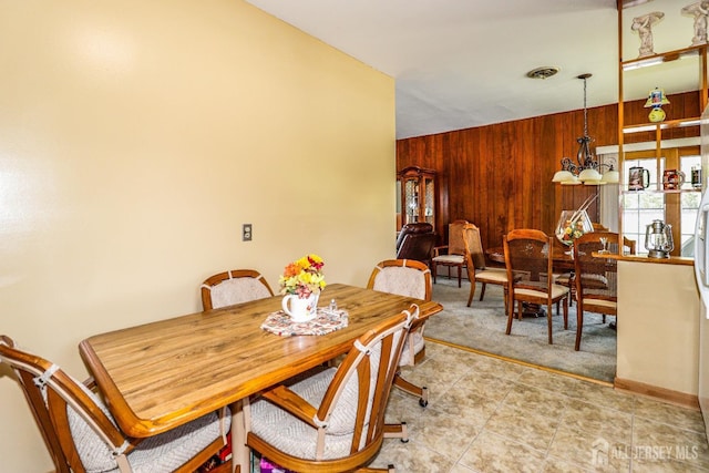 dining room with light tile patterned floors, light carpet, and wood walls