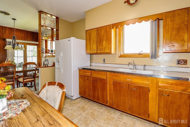 kitchen with brown cabinets, visible vents, a sink, and white fridge with ice dispenser