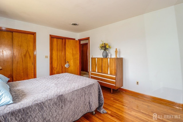 bedroom with visible vents, baseboards, and wood finished floors