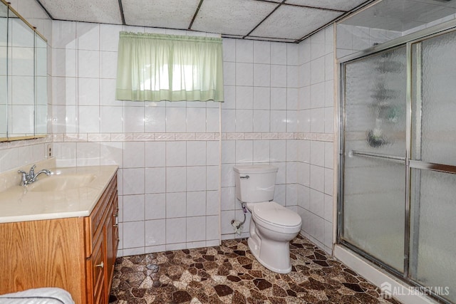bathroom with vanity, a stall shower, toilet, and tile walls