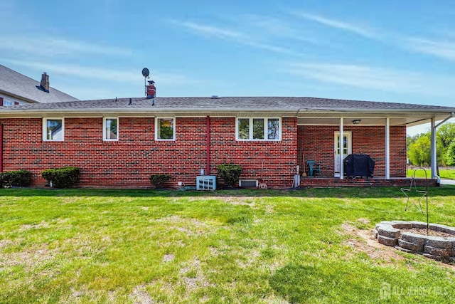 back of property with brick siding and a yard
