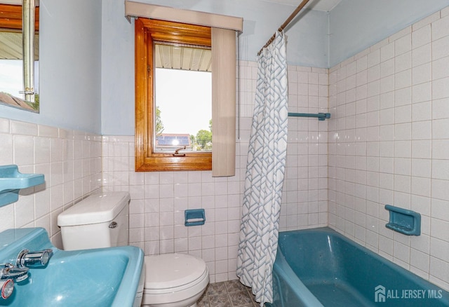 bathroom featuring a sink, tile walls, shower / bath combo with shower curtain, and toilet