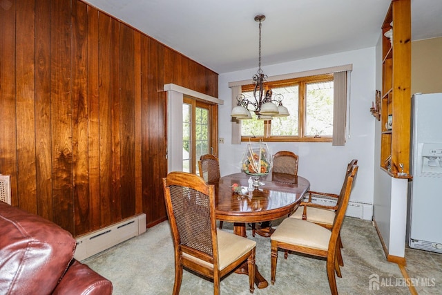 dining area with wooden walls, light colored carpet, and baseboard heating