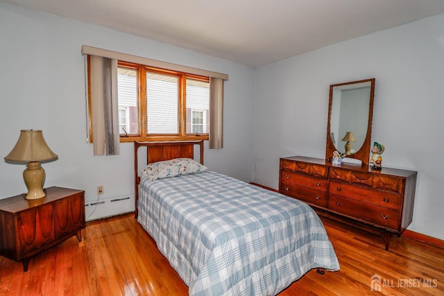 bedroom featuring baseboard heating and hardwood / wood-style floors