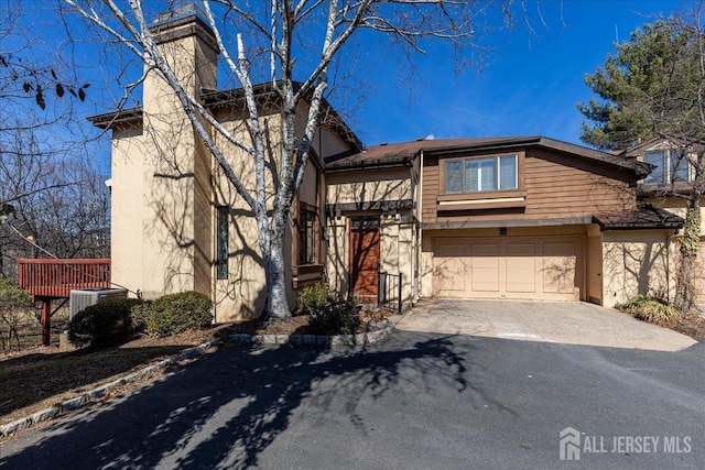 view of front of property featuring central air condition unit, an attached garage, driveway, and stucco siding