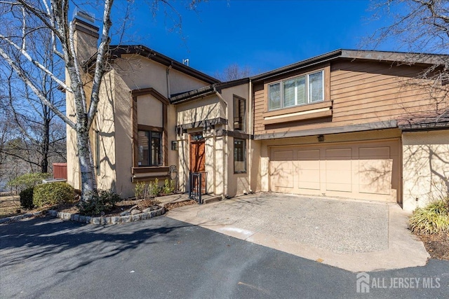 view of front of property with stucco siding, an attached garage, and driveway