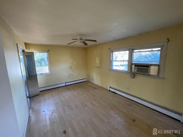 empty room featuring light wood-type flooring, a baseboard radiator, and a healthy amount of sunlight