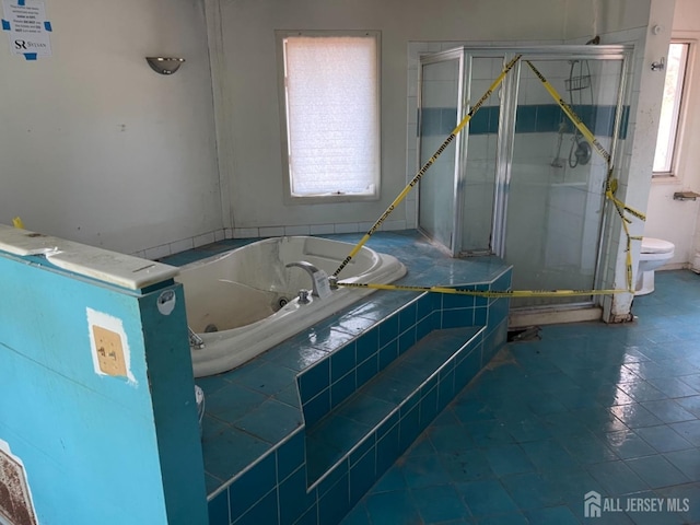 bathroom featuring toilet, a garden tub, and a shower stall