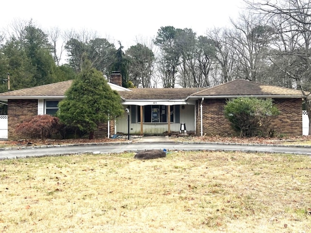 single story home with a chimney, a front lawn, and brick siding