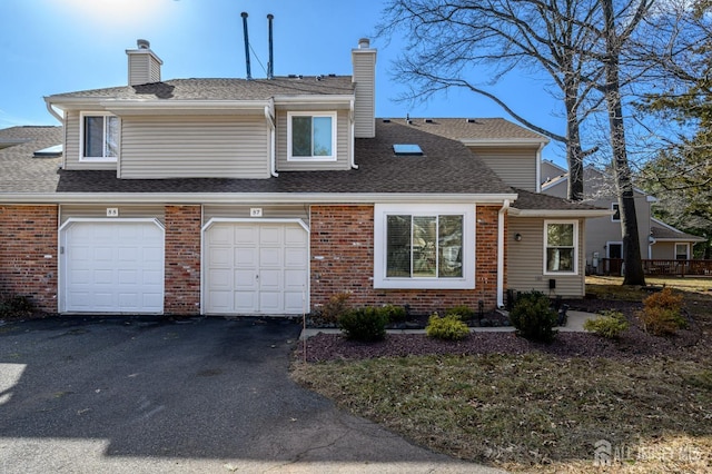 view of front of property featuring driveway, a shingled roof, a chimney, and brick siding