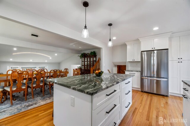 kitchen with white cabinets, a kitchen island, stainless steel fridge, and light hardwood / wood-style floors