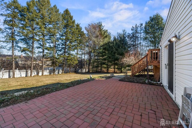 view of patio featuring fence and stairway