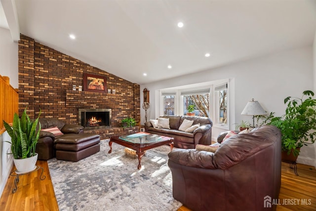 living room with vaulted ceiling, a brick fireplace, wood finished floors, and recessed lighting