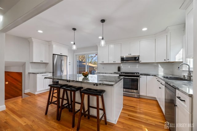 kitchen featuring white cabinetry, stainless steel appliances, sink, and a kitchen island