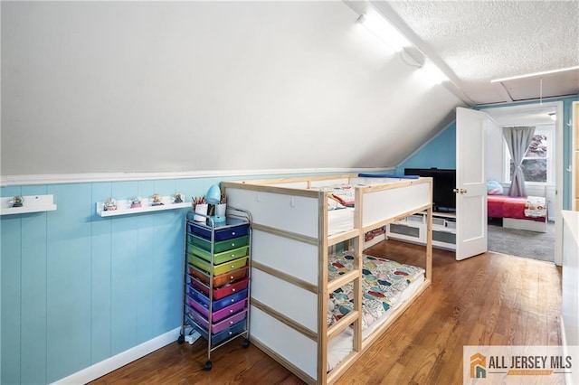 bedroom featuring wood finished floors, a textured ceiling, and vaulted ceiling
