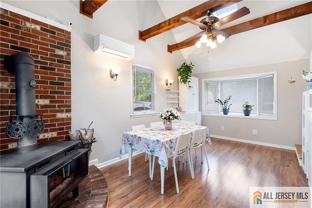 dining space with a wood stove, an AC wall unit, wood finished floors, and baseboards