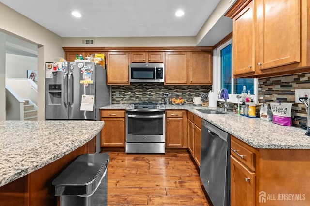473 E Sayre Dr, Middlesex, NJ 08540 - kitchen with stainless steel appliances, wood finished floors, brown cabinets, and recessed lighting