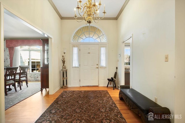 entrance foyer with a notable chandelier, light wood finished floors, and ornamental molding