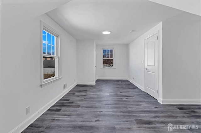 unfurnished room featuring a wealth of natural light and dark hardwood / wood-style flooring