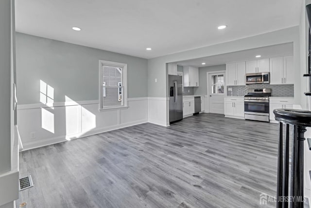 kitchen featuring white cabinets, backsplash, stainless steel appliances, and light hardwood / wood-style floors