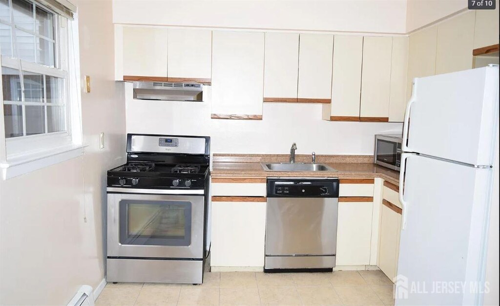 kitchen featuring appliances with stainless steel finishes, white cabinets, a wealth of natural light, and sink