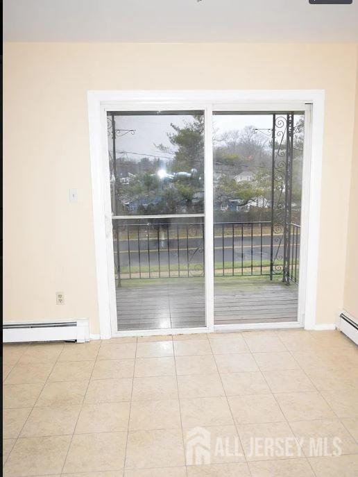 tiled spare room with a baseboard heating unit