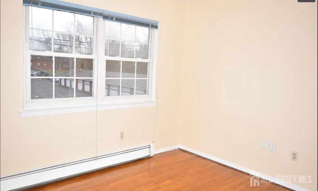 spare room with a baseboard heating unit and hardwood / wood-style flooring