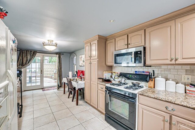 kitchen featuring light tile patterned floors, backsplash, light brown cabinetry, light stone countertops, and gas stove