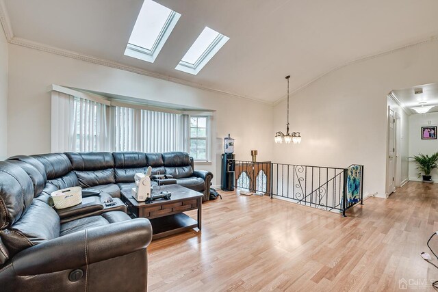 living room with vaulted ceiling with skylight, crown molding, and hardwood / wood-style floors