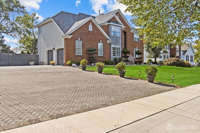 view of front facade featuring fence, a front lawn, a garage, decorative driveway, and brick siding