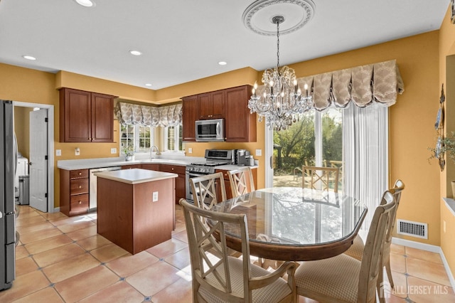 kitchen featuring visible vents, a kitchen island, an inviting chandelier, stainless steel appliances, and light countertops