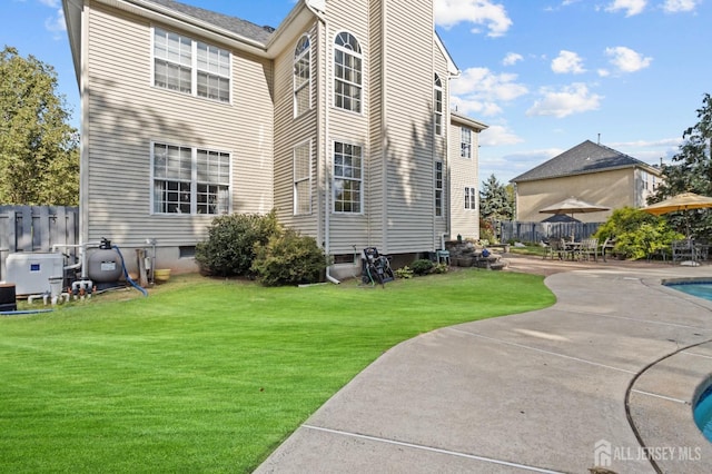 rear view of property featuring a patio area, a fenced in pool, a lawn, and fence