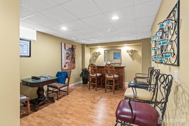 playroom with wood finished floors, recessed lighting, a bar, a paneled ceiling, and baseboards