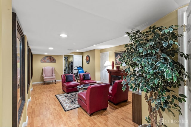 living room featuring recessed lighting, light wood-type flooring, baseboards, and a fireplace