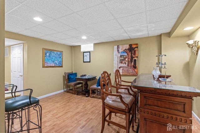 dining room with a drop ceiling, light wood-type flooring, baseboards, and recessed lighting